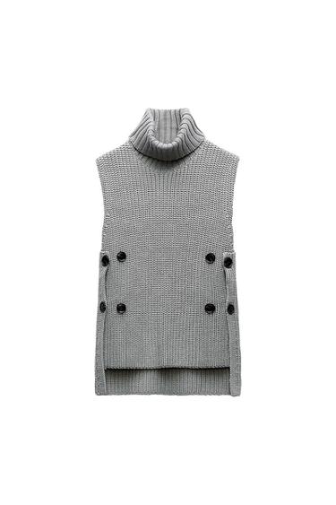 Chunky knit grey gilet with a high neck and black buttons on the sides, on a white background.