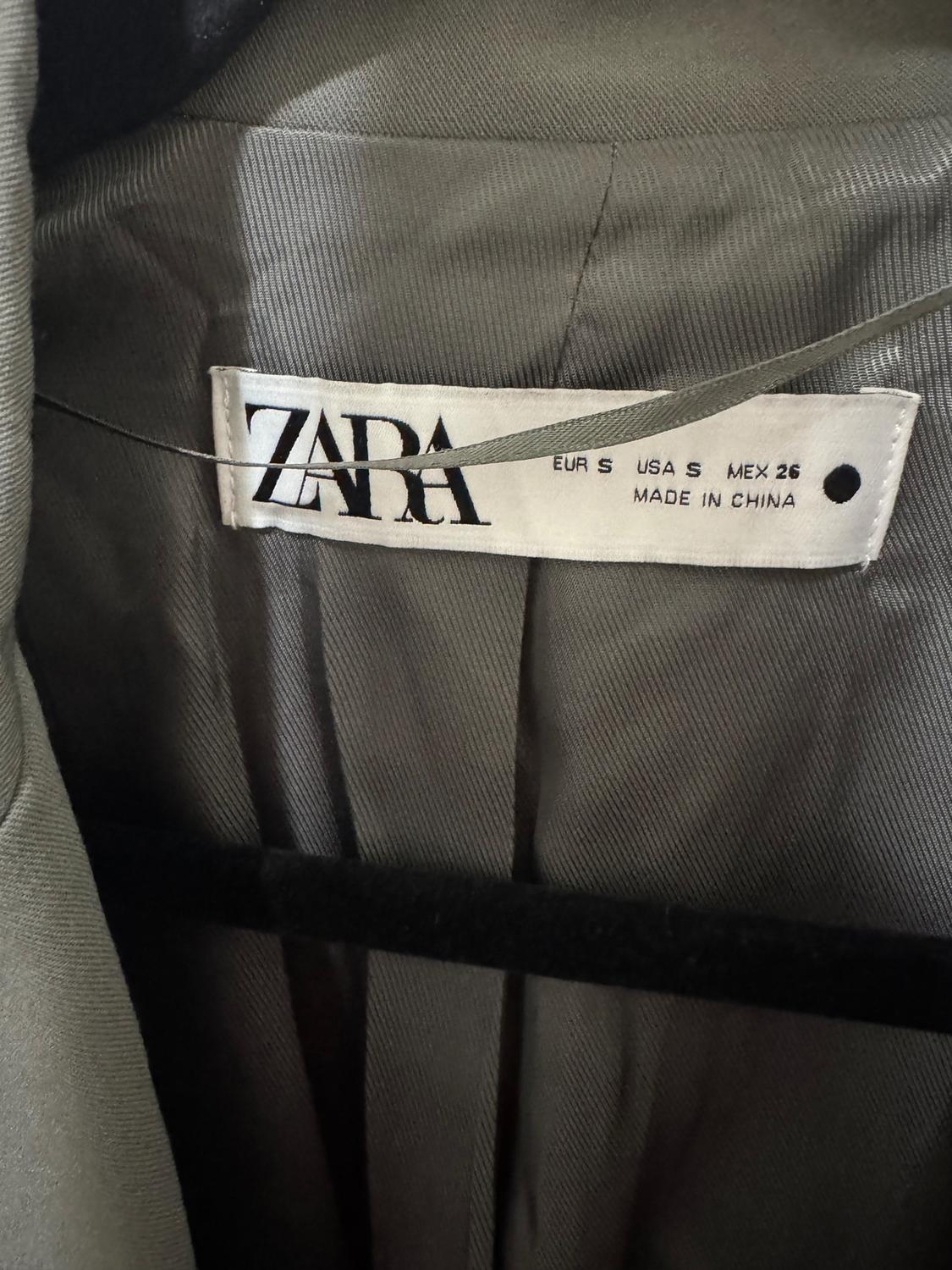 Zara clothing tag on gray fabric, showing sizes EUR S, USA S, MEX 26 and "MADE IN CHINA".