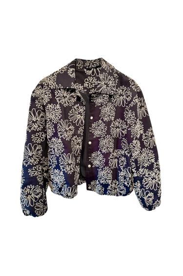 Black jacket with white floral print, front buttons and classic collar. Modern and eye-catching design.