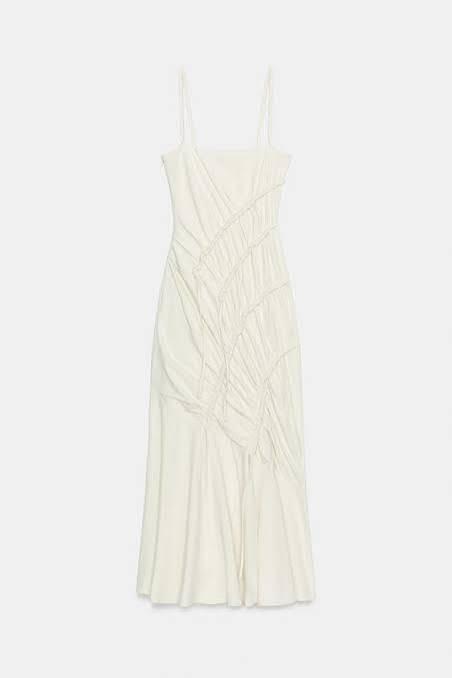 White dress with thin straps and asymmetric ruched detailing at the front, against a light background.