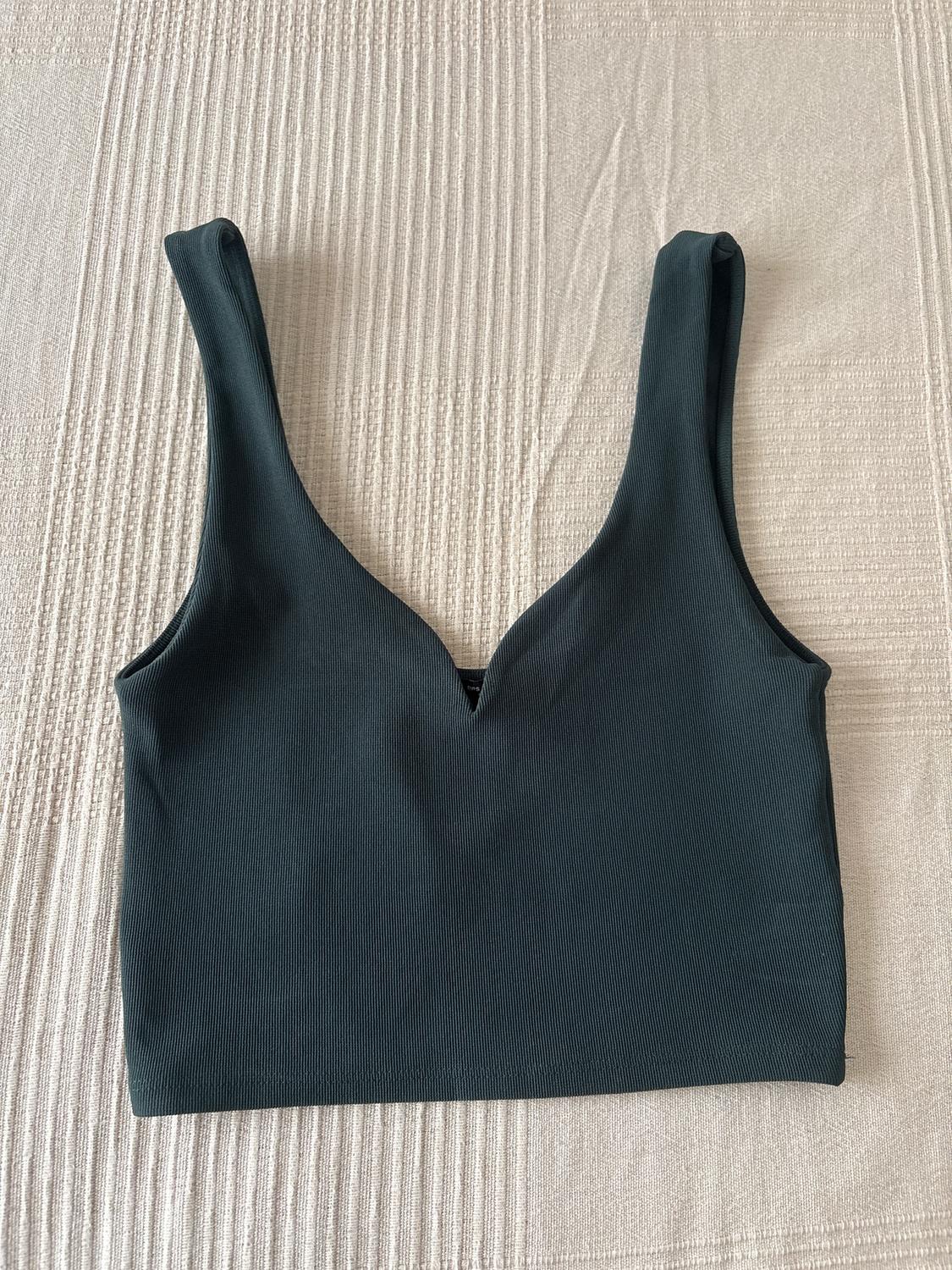 Μαύρο crop top με λαιμόκοψη V πάνω σε μπεζ ανάγλυφη επιφάνεια.