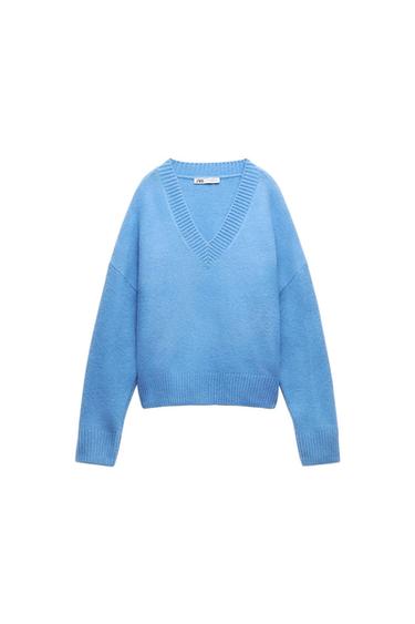 Light blue knitted jumper with a V-neck and long sleeves on a white background. Label with the text ZARA.