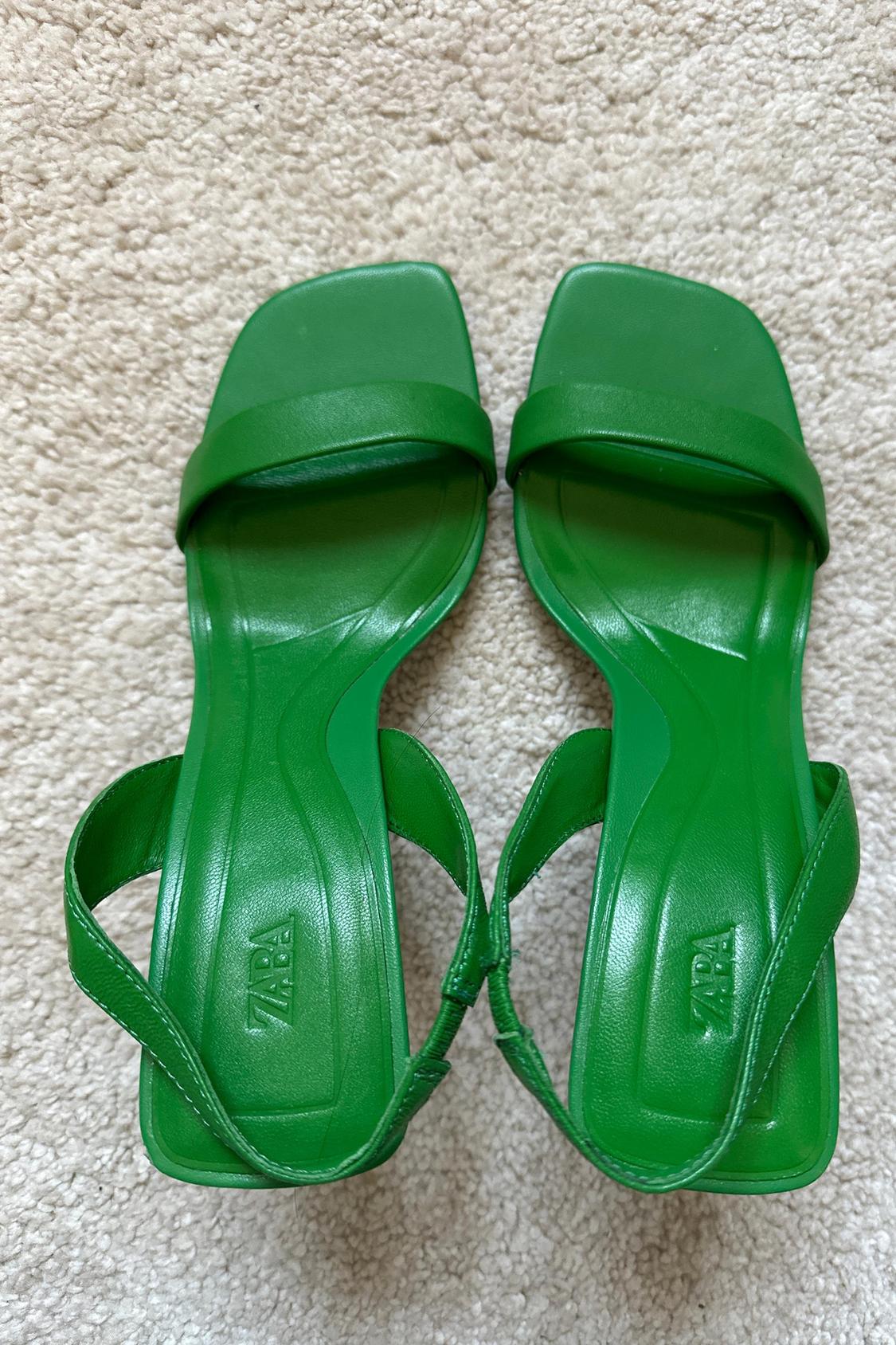 Front view of green sandals with wide straps and insole with 'ZARA' logo.