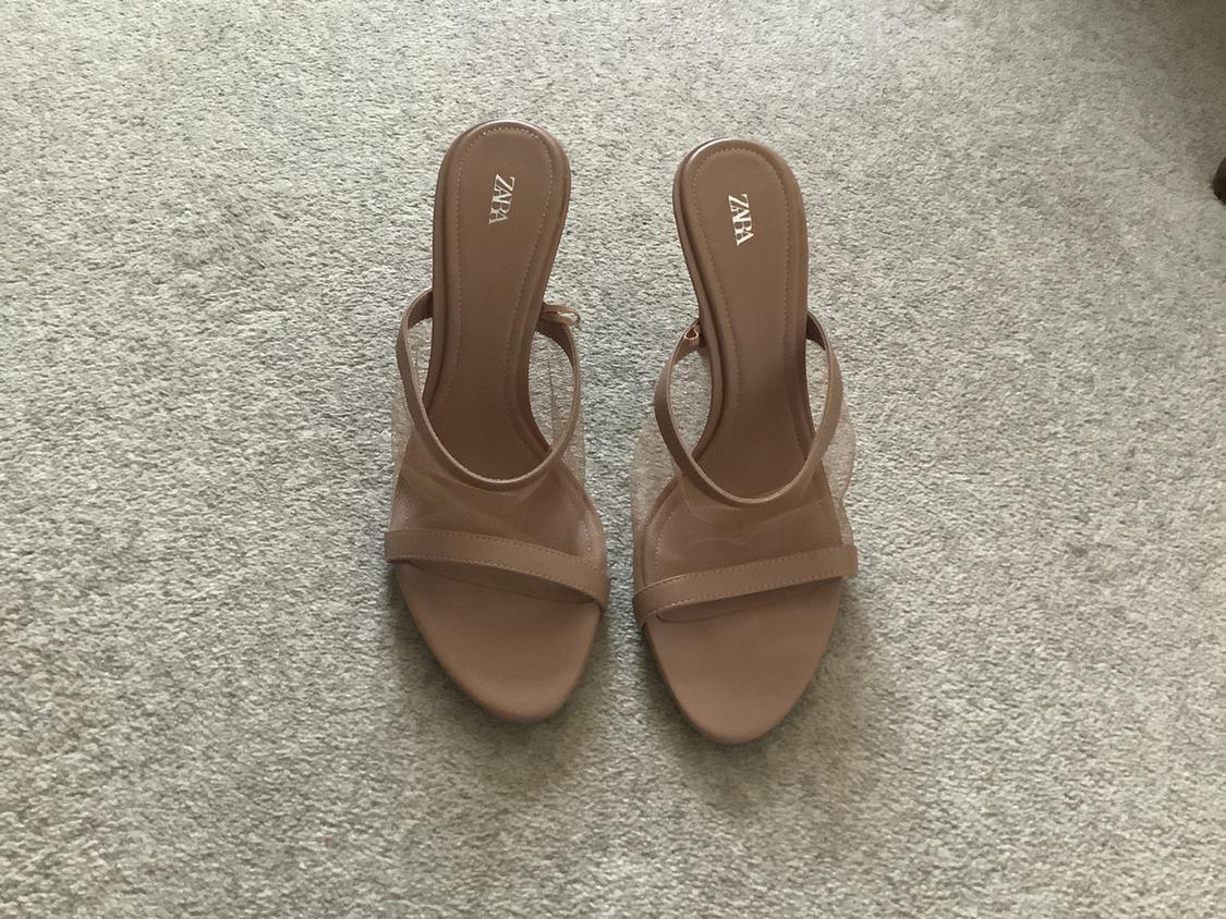 Pair of nude heeled sandals with straps and sheer mesh detail on a light-coloured rug. ZARA text printed on the insoles.