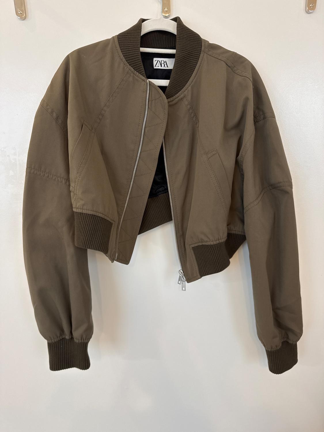Front view of a brown short jacket with a zipper and side pockets.