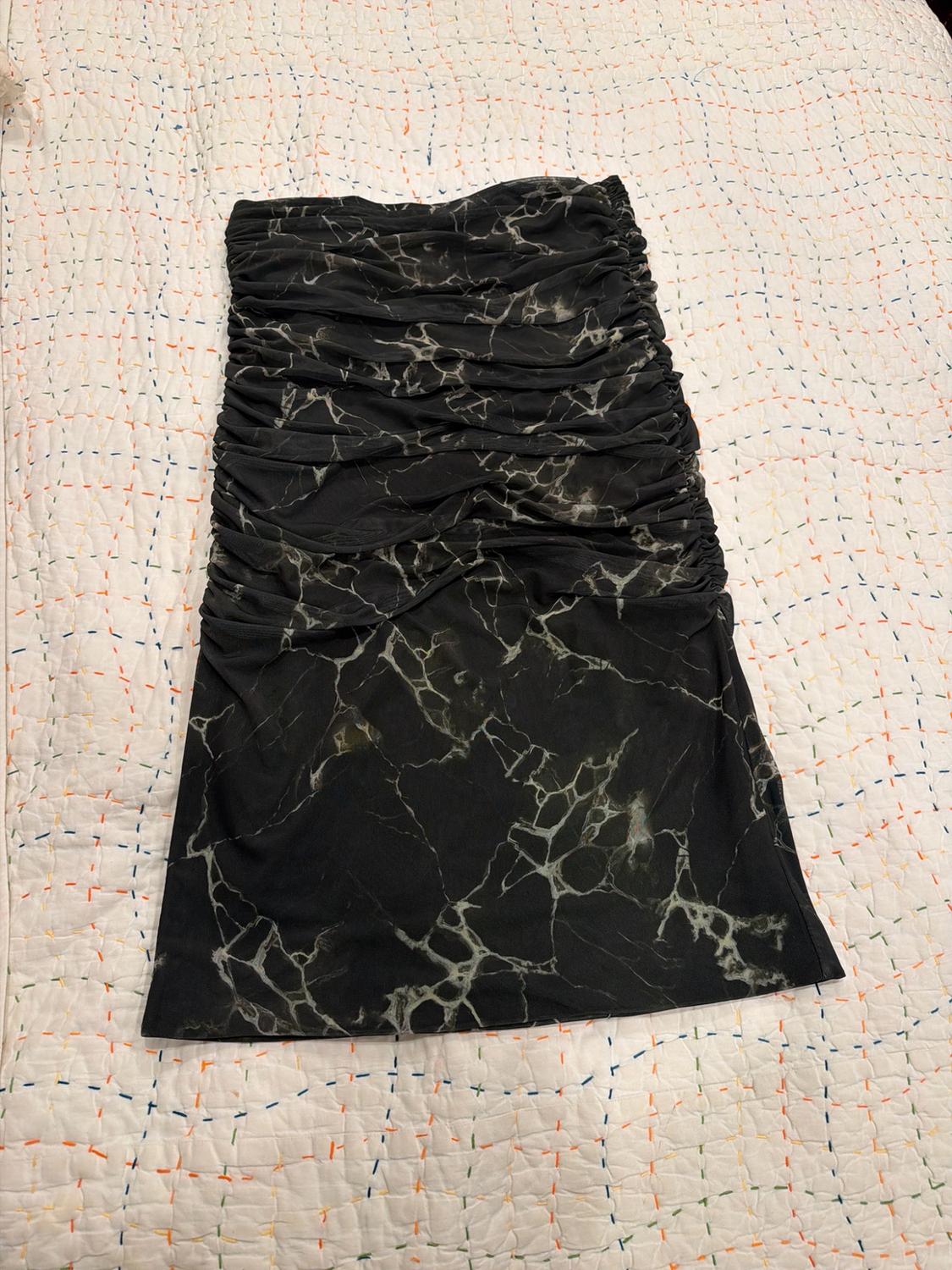 Black skirt with marble print and ruching, laid out on a white quilt with colorful stitching.