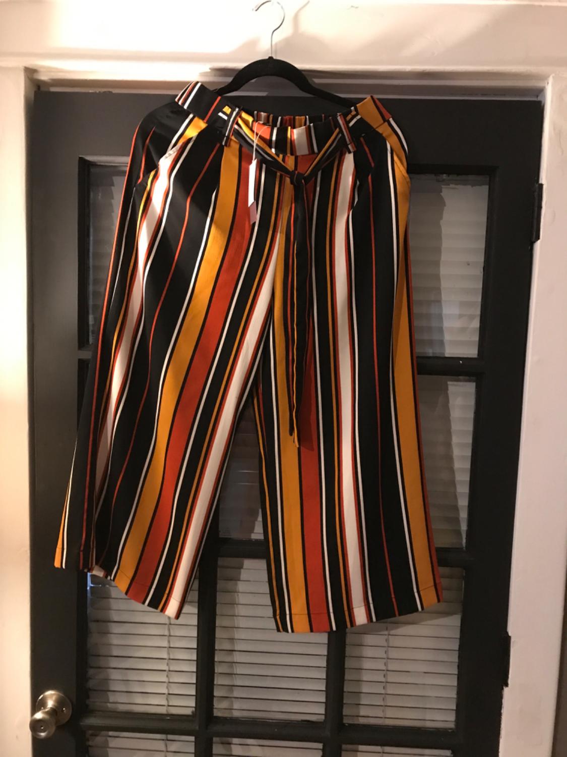 Front view of orange, black and white vertical striped shorts with a matching belt.