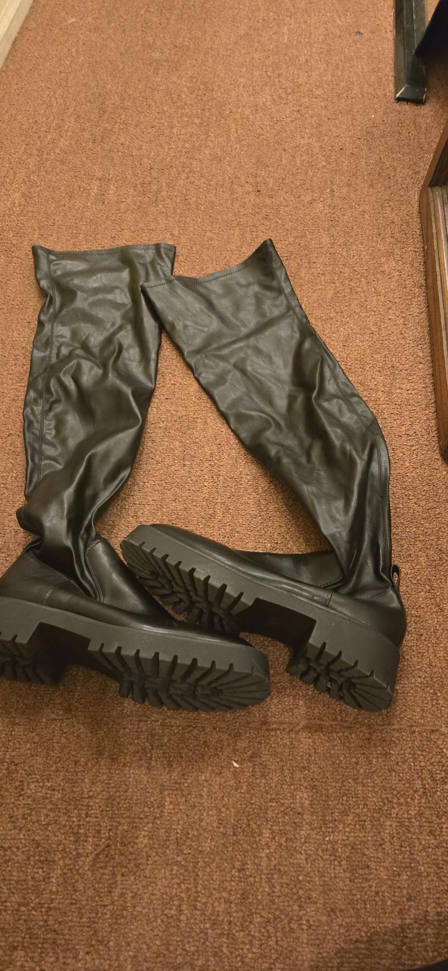 Top view of black high boots with thick sole and wrinkled texture.