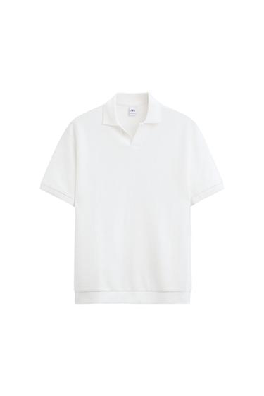 White short-sleeved polo shirt with classic collar and light texture. Visible label inside the neck. White background.