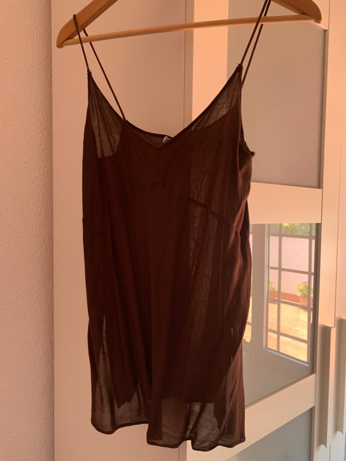 Front view of a brown dress with thin straps on a hanger.