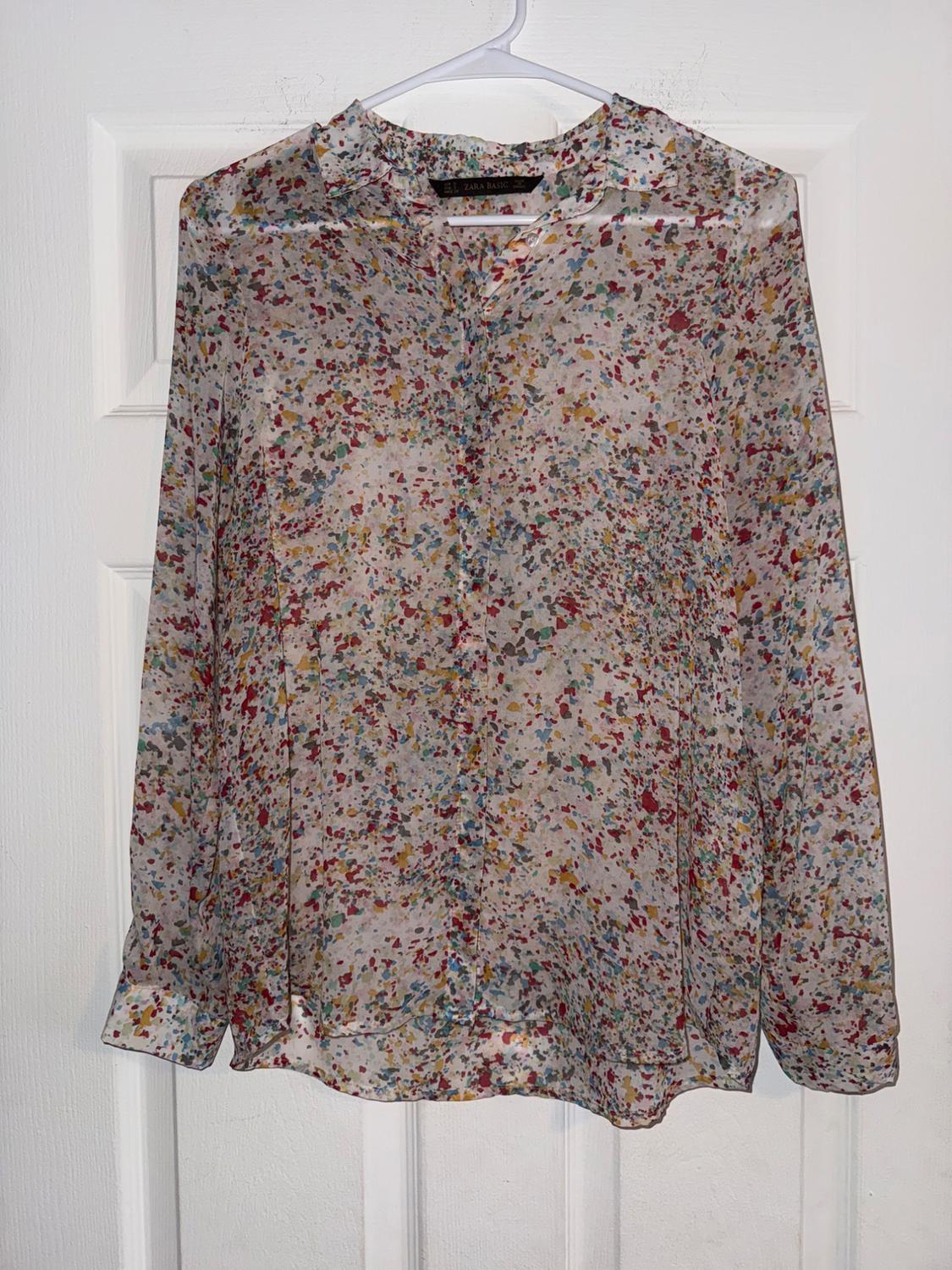 Chiffon blouse with a multicoloured print hanging on a white hanger over a white door. Visible label: "Zara Basic".