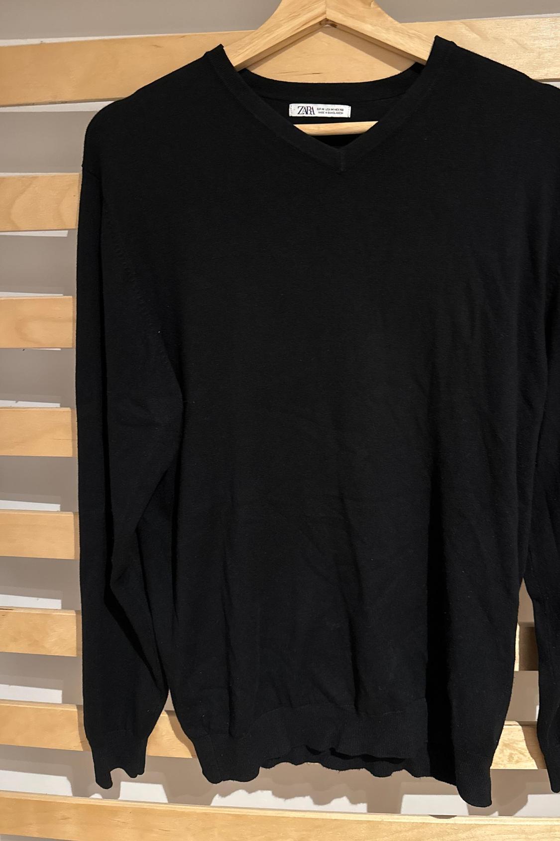 Front view of black jumper with V-neck and long sleeves.