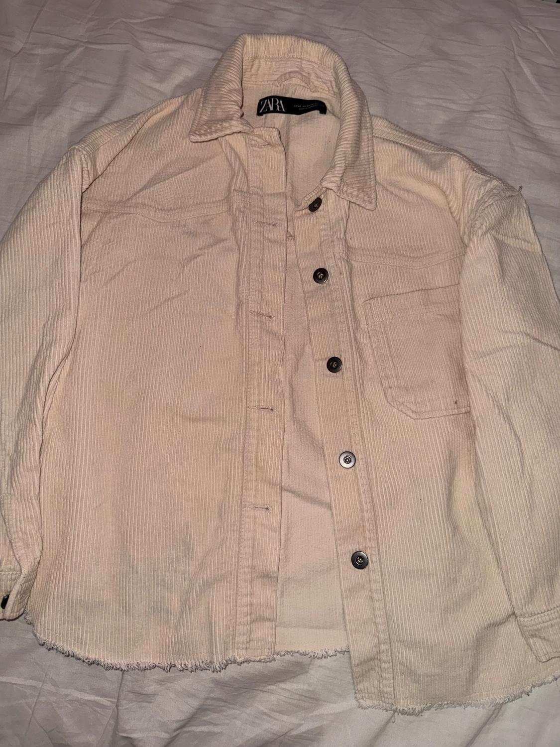 Beige corduroy shirt with dark buttons and chest pocket, on a white surface. Visible label with text "ZARA".