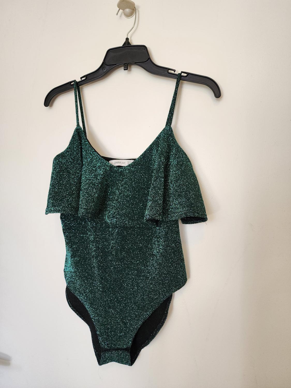 Front view of a bright green bodysuit with thin straps and ruffles on the chest.