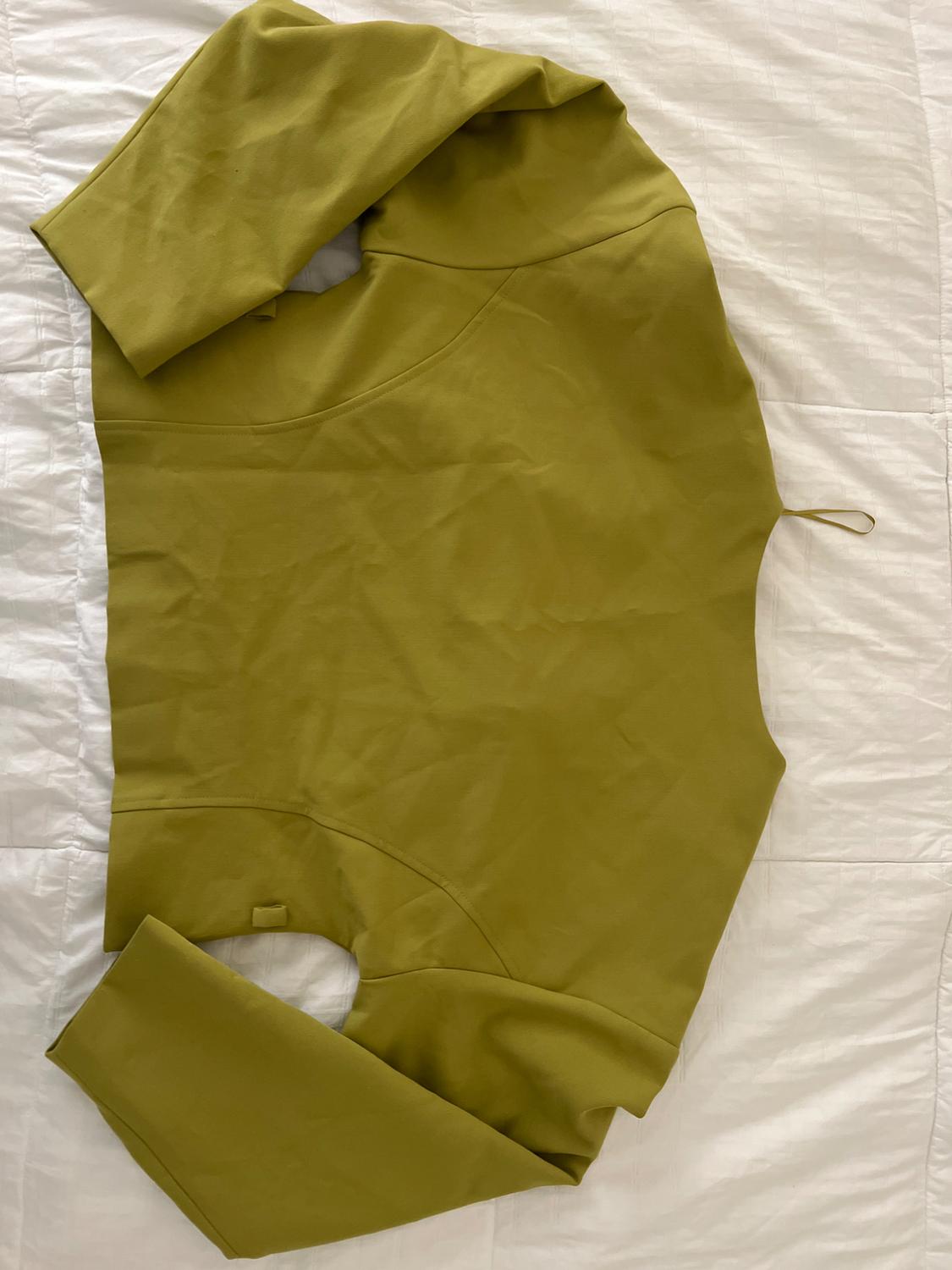 Olive green long-sleeve garment with seam details, laid out on a white sheet.