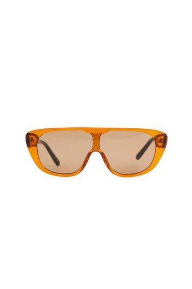Sunglasses with a translucent orange chunky frame, flat-top design, and light brown lenses on a white background.