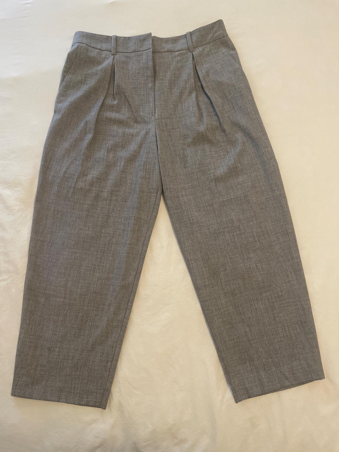 Grey lightweight fabric trousers with pleats, laid flat on a light surface. Classic and elegant design.