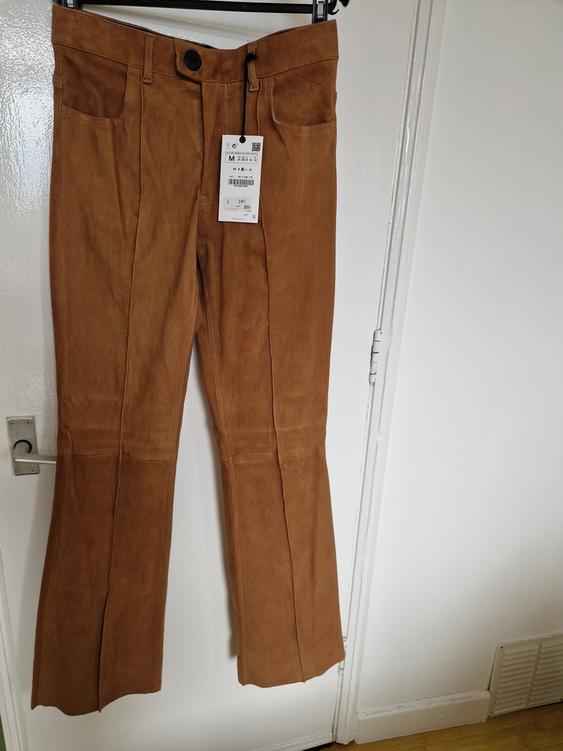 Brown flared trousers hanging on a hanger, with visible price tag indicating size M and a price of €34.99. White background.