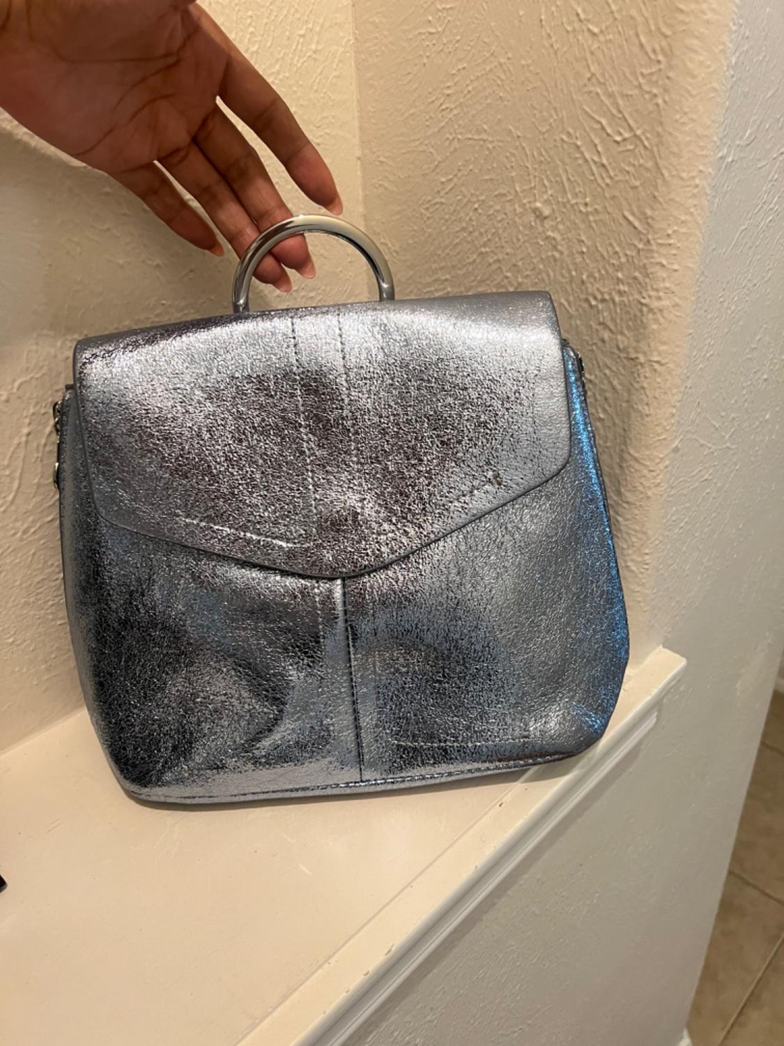 Close-up of a silver handbag with a circular metal handle.