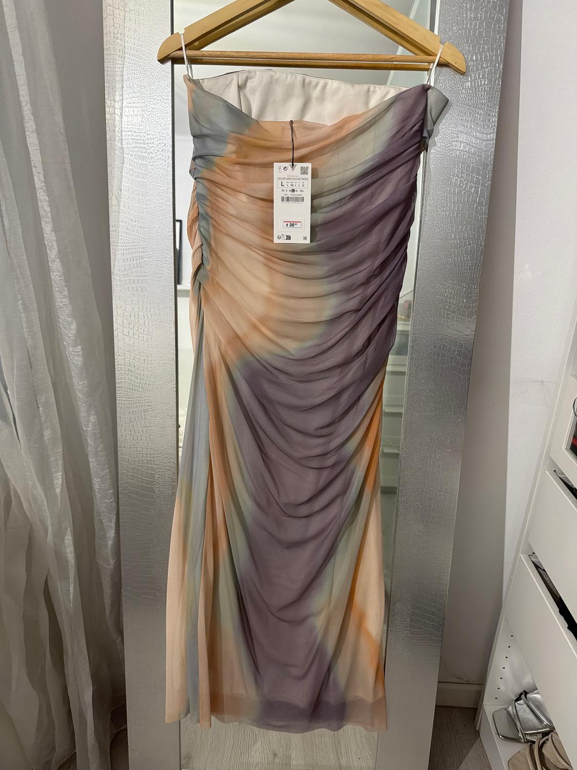 Long ombré dress in pastel shades hanging on a hanger in front of a mirror. Visible tag with a price of £49.95.