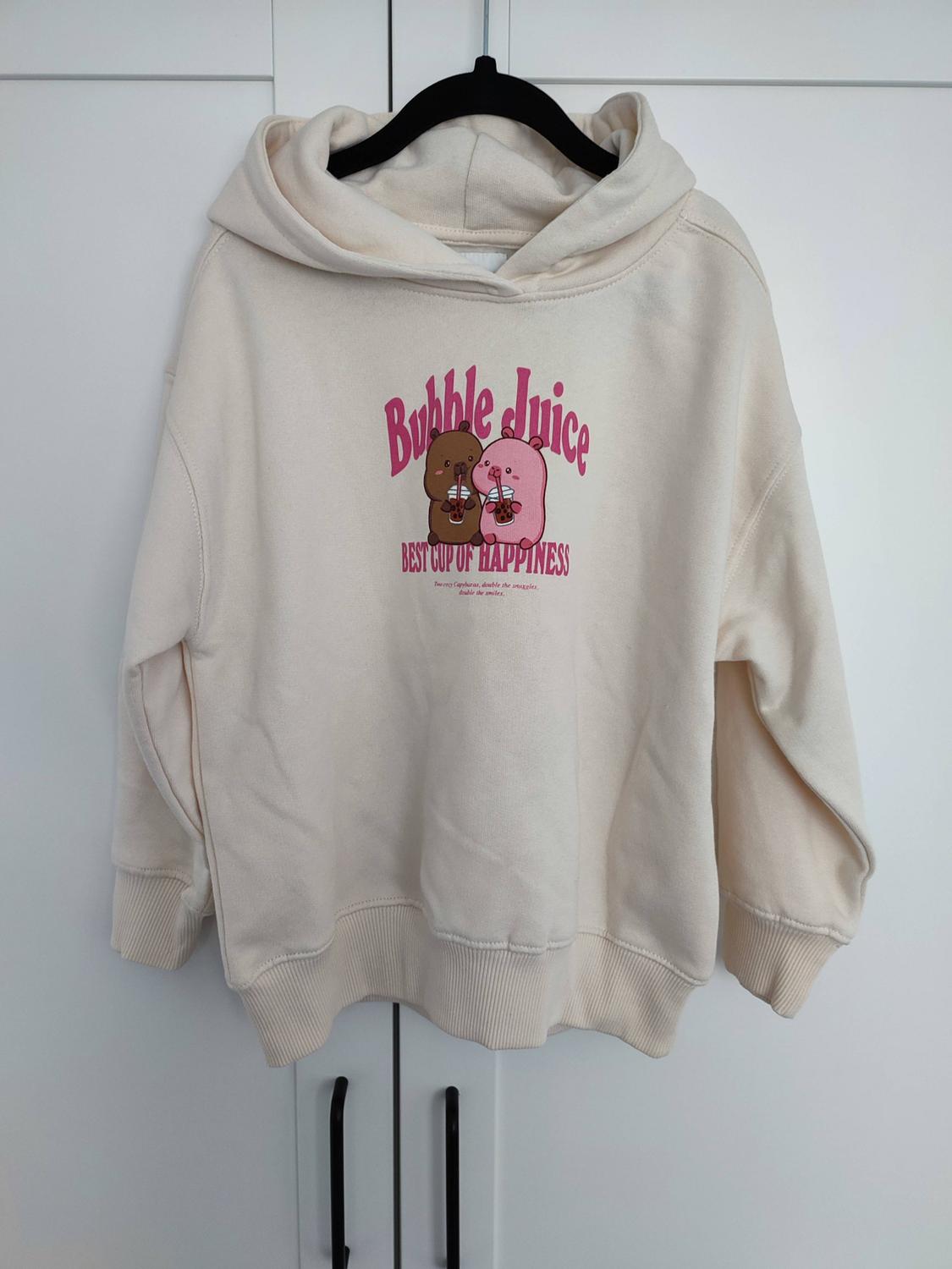 Cream hoodie with animals. Text: Bubble Juice BEST CUP OF HAPPINESS Two cosy Capybaras, double the snuggles, double the smiles.