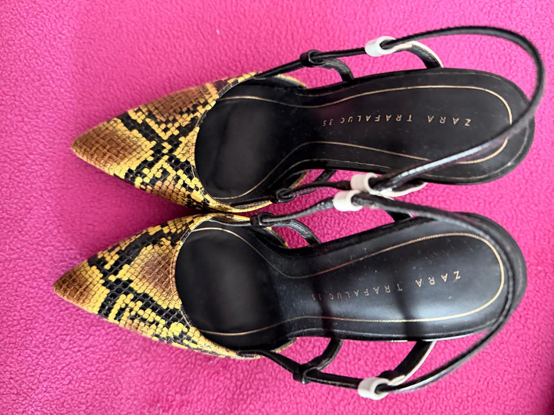 Snake print high heels in yellow and black tones on a pink background. Visible text: "ZARA TRAFALUC 38".