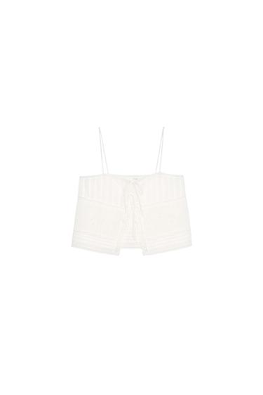 Front view of a white top with spaghetti straps and tie detailing at the front.