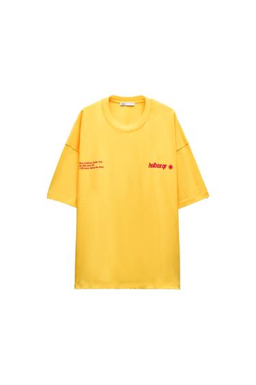 Front view of a yellow t-shirt with the text 'holbox qr' and the address 'Plaza Las Américas, Avenida Tulum...'.