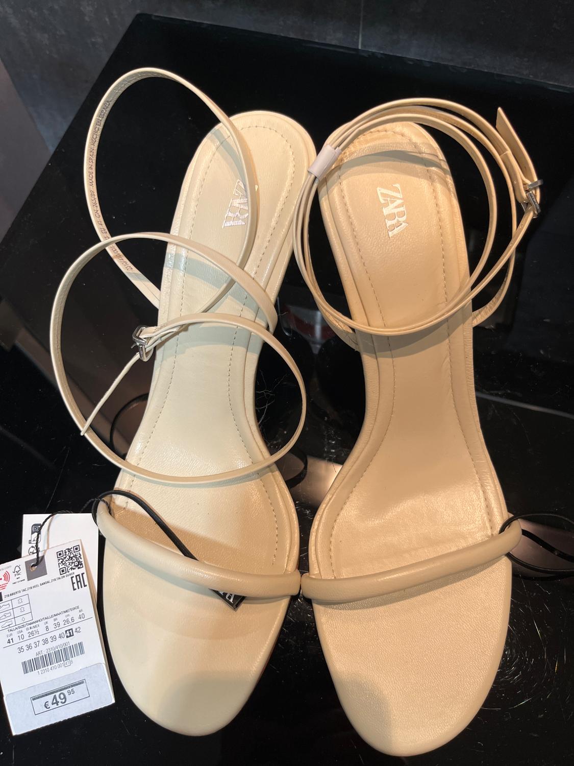 Μπεζ πέδιλα με λεπτά λουράκια με τιμή €49,95, σε μαύρο φόντο. Ορατό κείμενο: "ZARA".