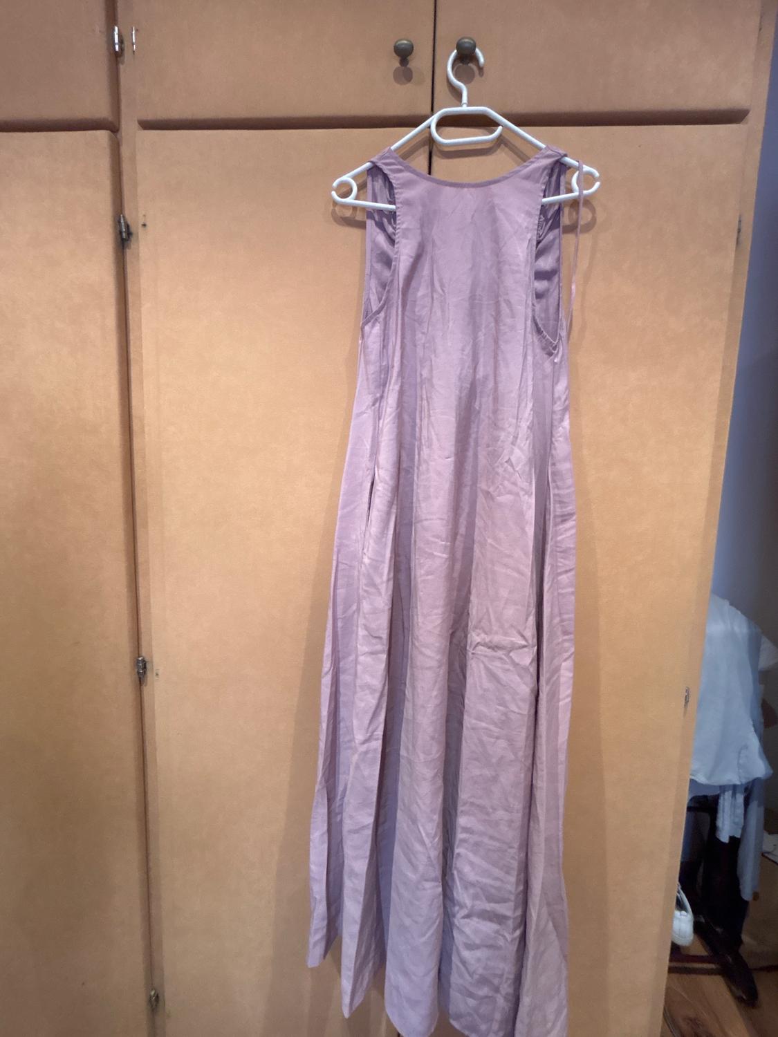 Lilac sleeveless maxi dress hanging on a white hanger in front of a light wood wardrobe.