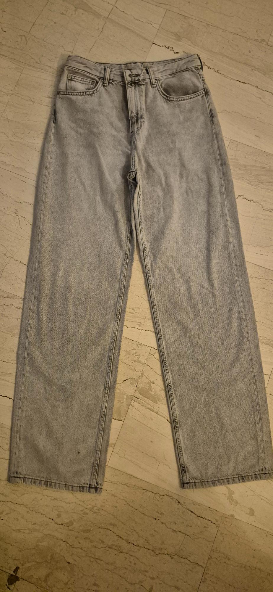 Grey straight-cut jeans on a light marble floor, showing pocket and seam details.