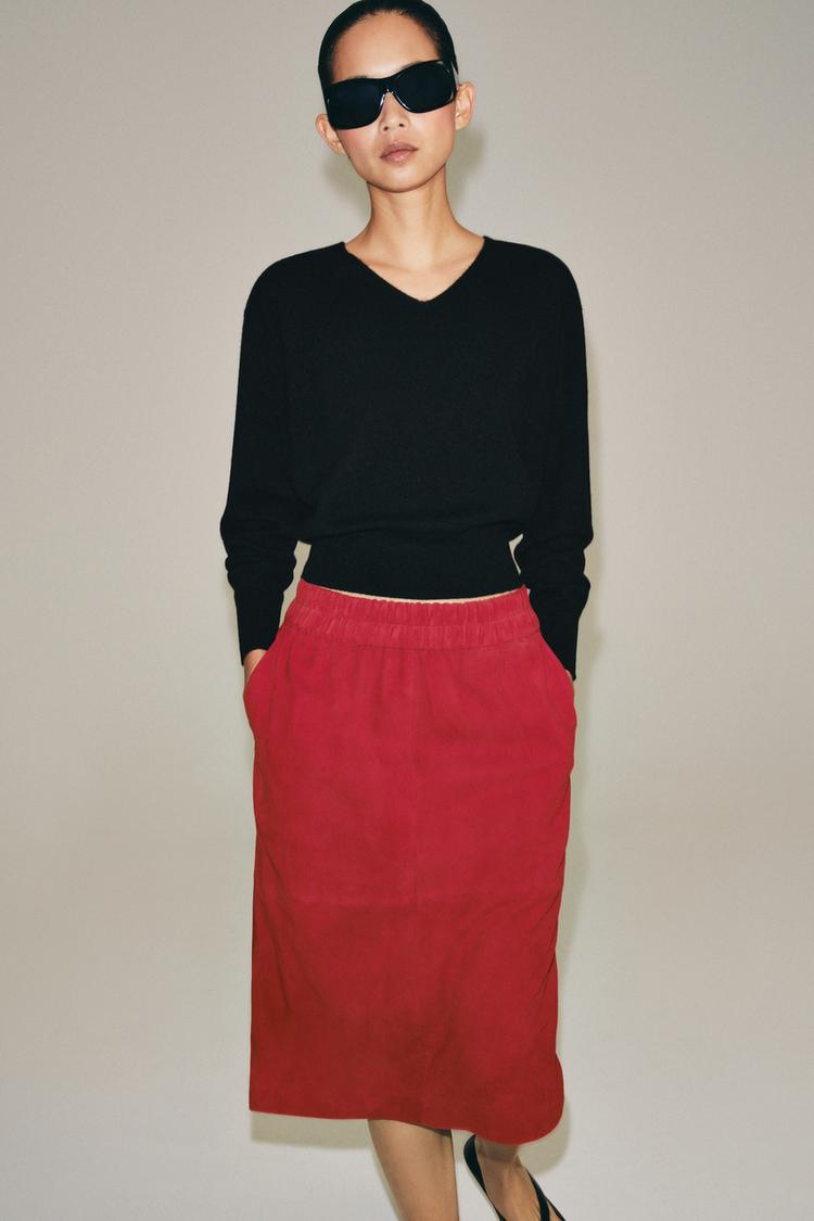 Black long-sleeved V-neck jumper set with a red midi skirt featuring an elasticated waist and side pockets.