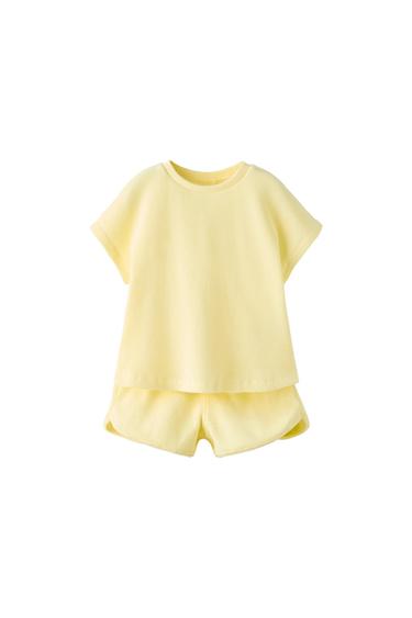 Light yellow ribbed knit set consisting of a short-sleeved T-shirt and shorts on a white background.