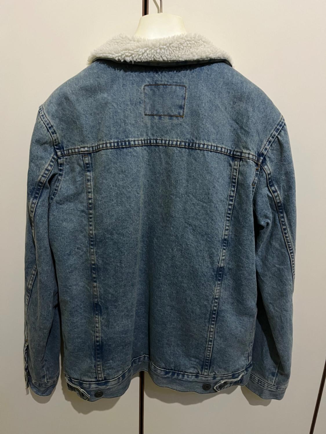 Blue denim jacket with a wool collar, rear view. Displayed on a mannequin in front of a white background.
