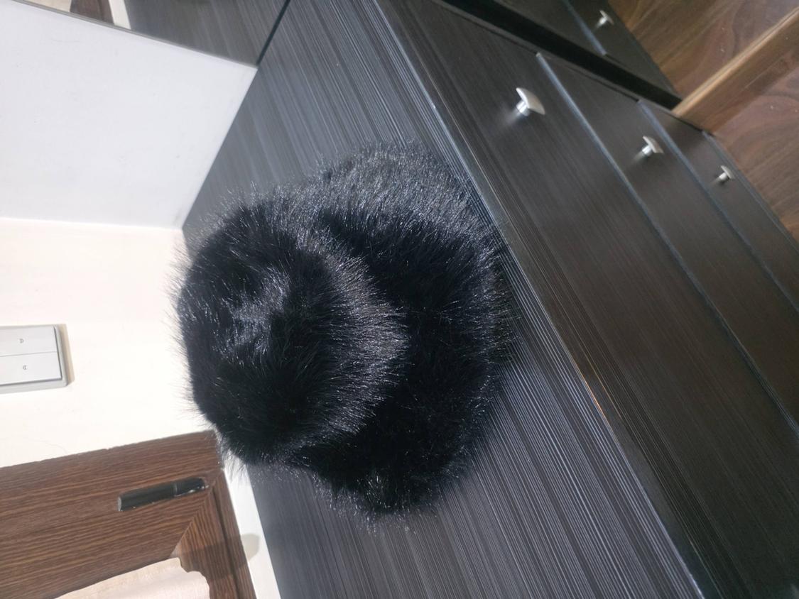 Black hairnet on a dark wooden chest of drawers with silver handles. Casual setting with a white wall and a door in the background.
