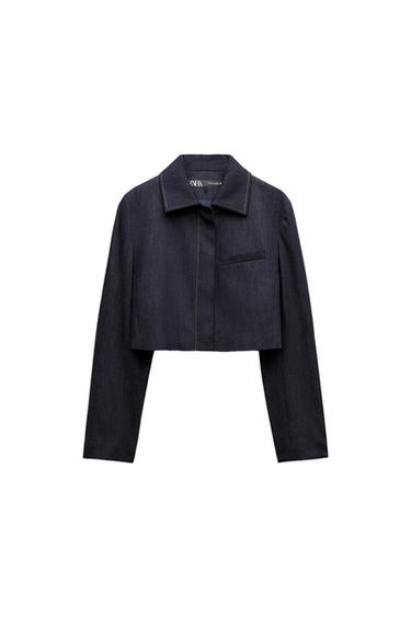 Dark blue denim cropped jacket with classic collar and chest pocket. Visible Zara tag on the inside of the neck.