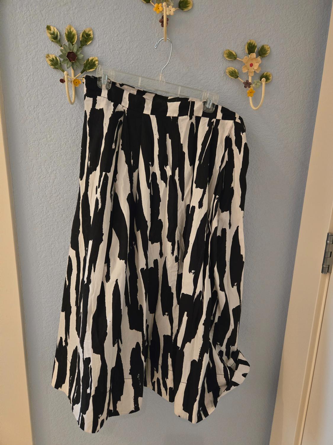 Hanging skirt with a black and white abstract print, against a light blue wall with decorative flower hooks.