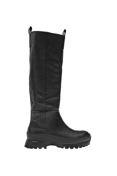 Side view of a black high boot with a thick sole and a rough texture.