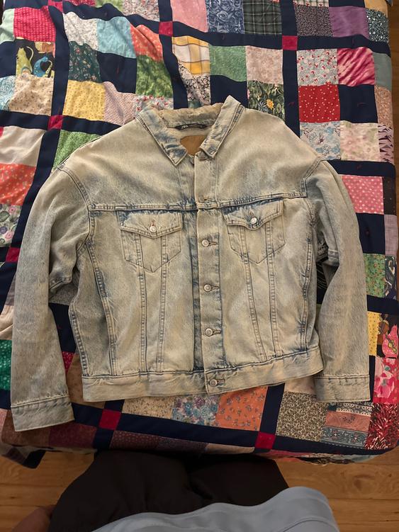Light blue denim jacket on a colorful patchwork quilt with varied patterns.