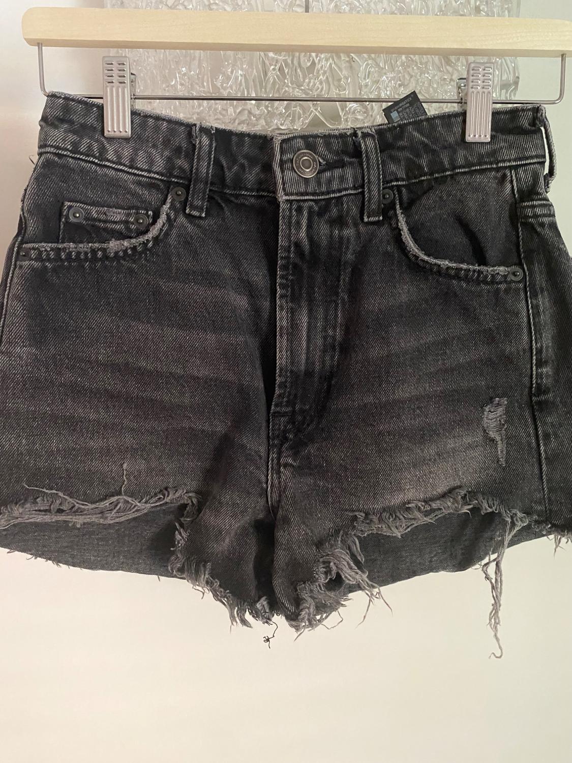 Close-up of black distressed denim shorts with front pockets and belt loops.