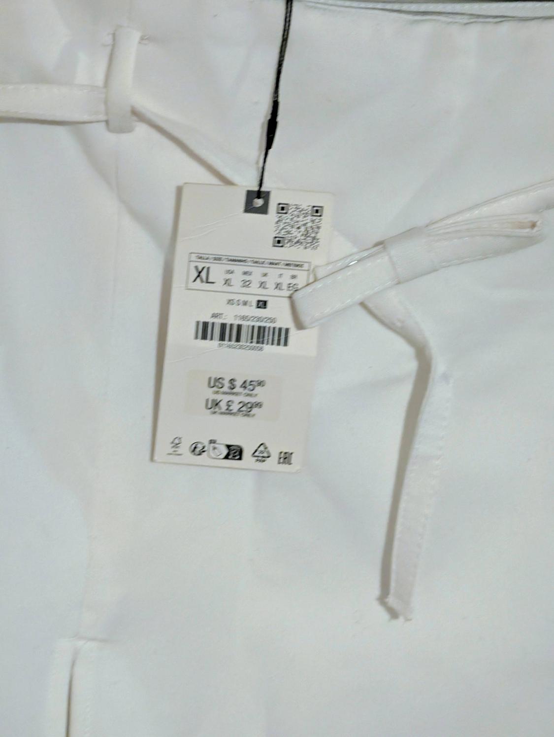 Hang tag on white pants, size XL, price US $45, UK £29. Includes QR code and care symbols.