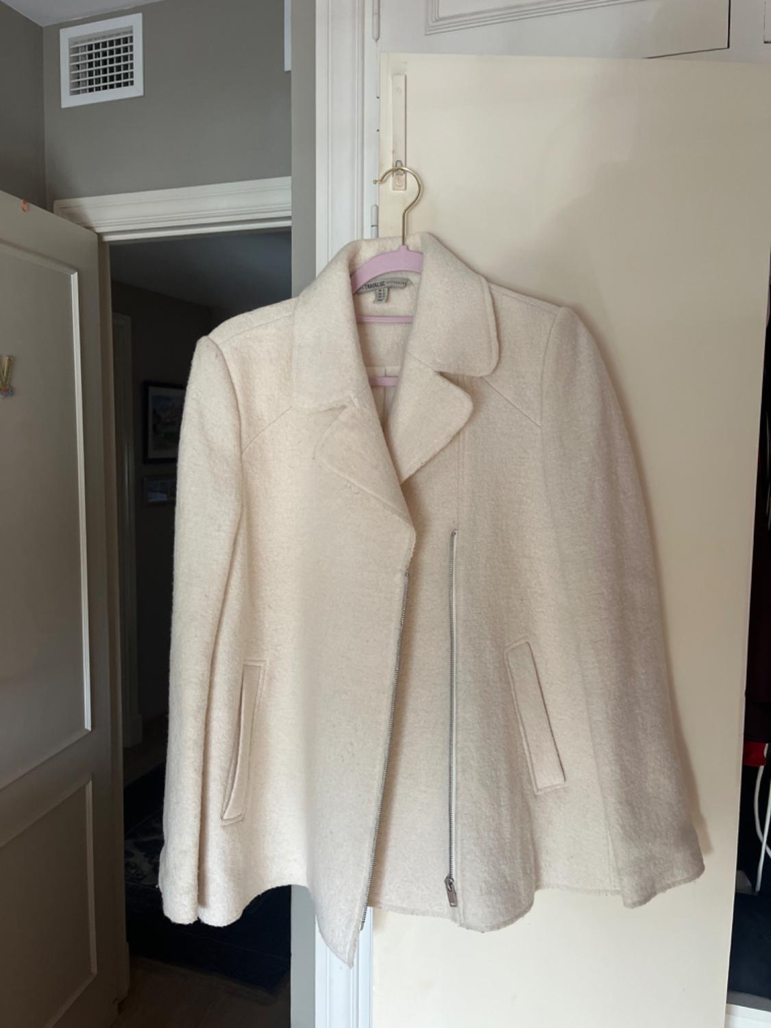 Front view of a beige jacket with a diagonal zip and side pockets.