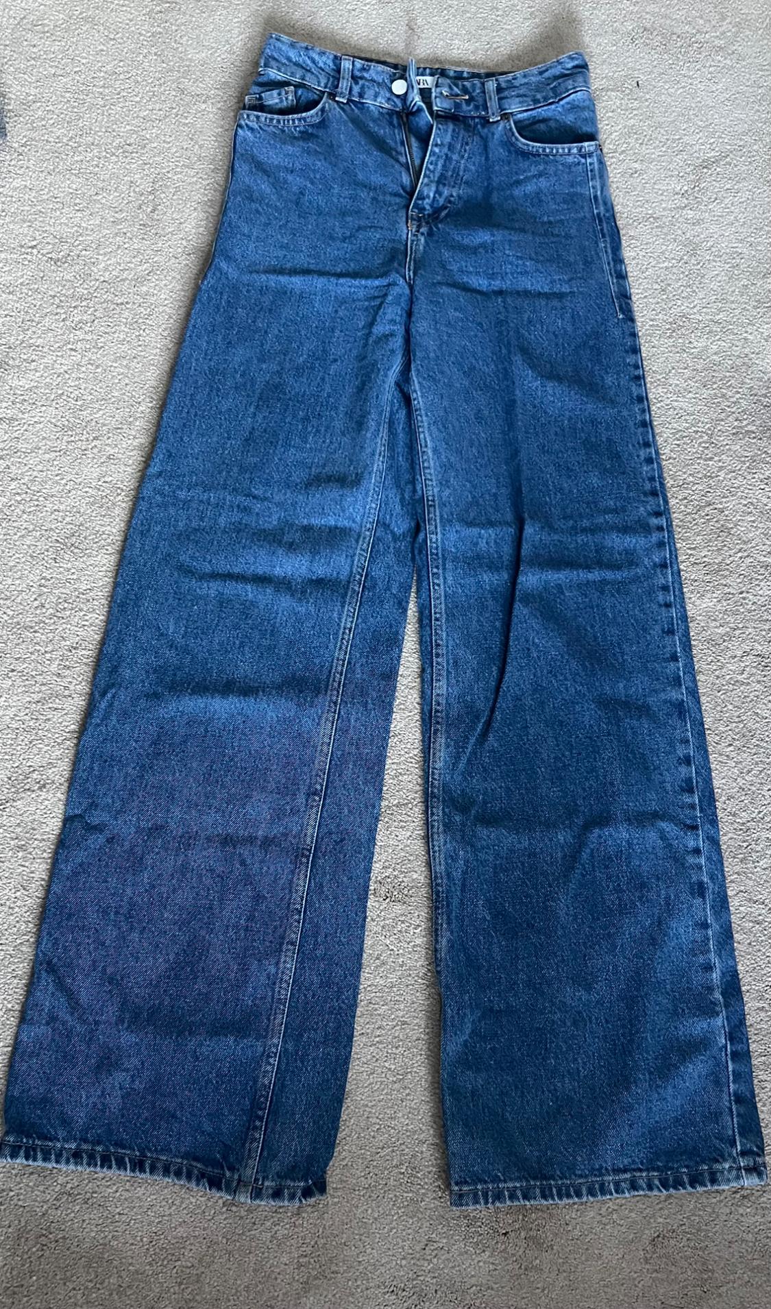 Front view of wide blue denim jeans with front and back pockets.