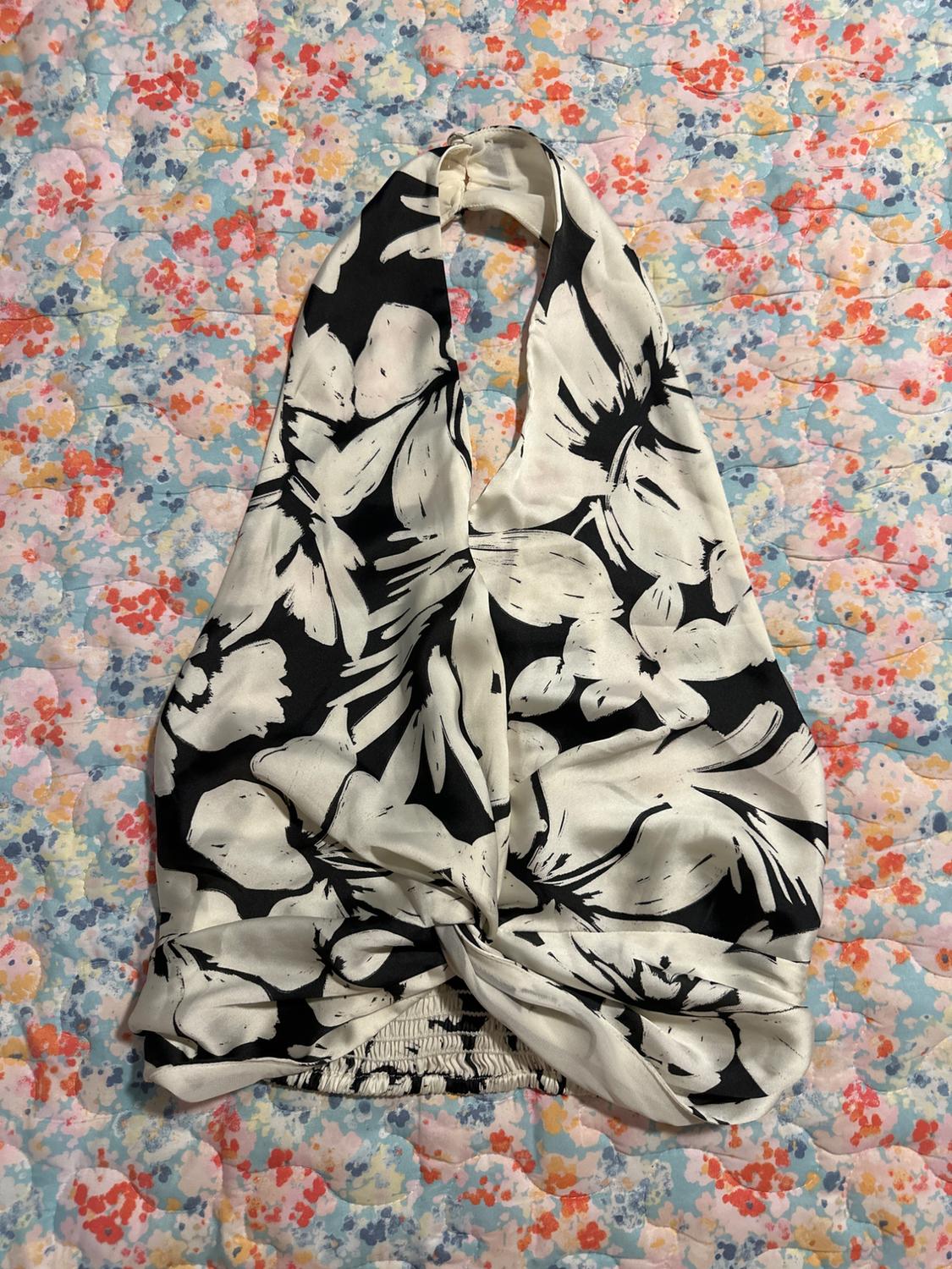 Black and white sleeveless top with a floral print on a colourful quilt background with a small flower design.