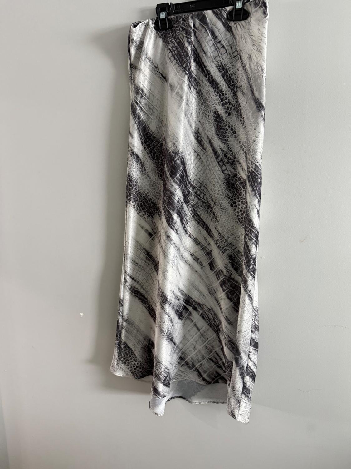 Long skirt hanging on a hanger, with a black and white snake print, on a light gray background.