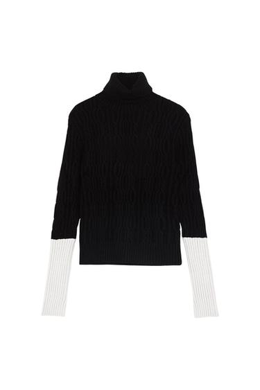 Black turtleneck sweater with long sleeves in white contrast, knit fabric with cable design on a white background.