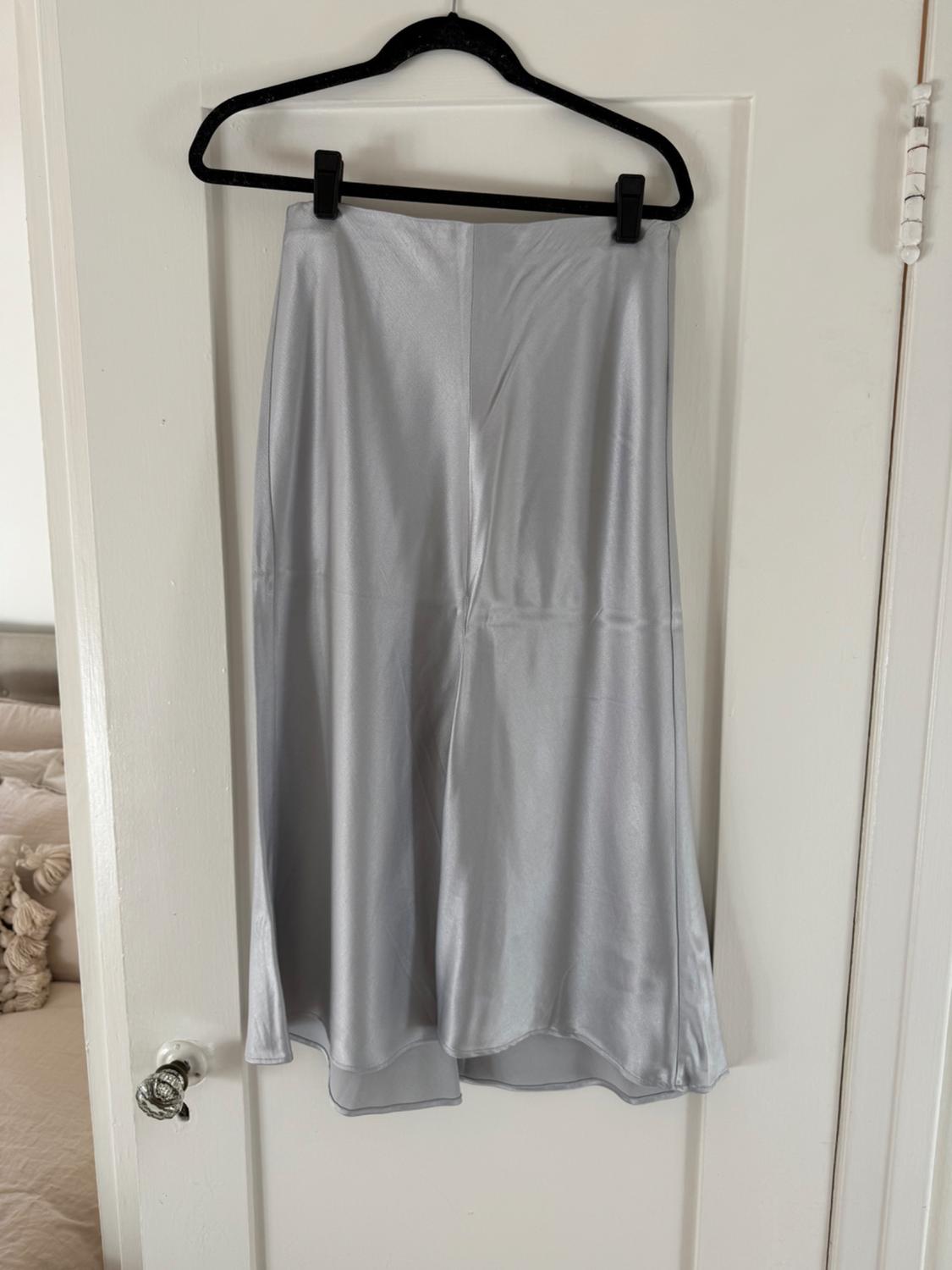 Front view of a shiny gray skirt hanging on a hanger.