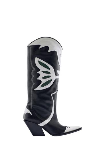Side view of a black heeled boot with white and green design, pointed toe.