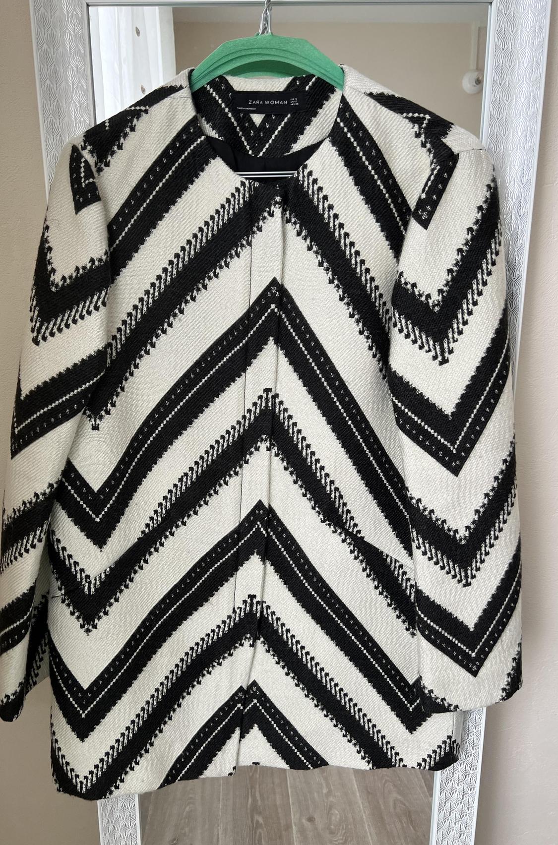Front view of jacket with black and white zigzag print, round neck and front fastening.