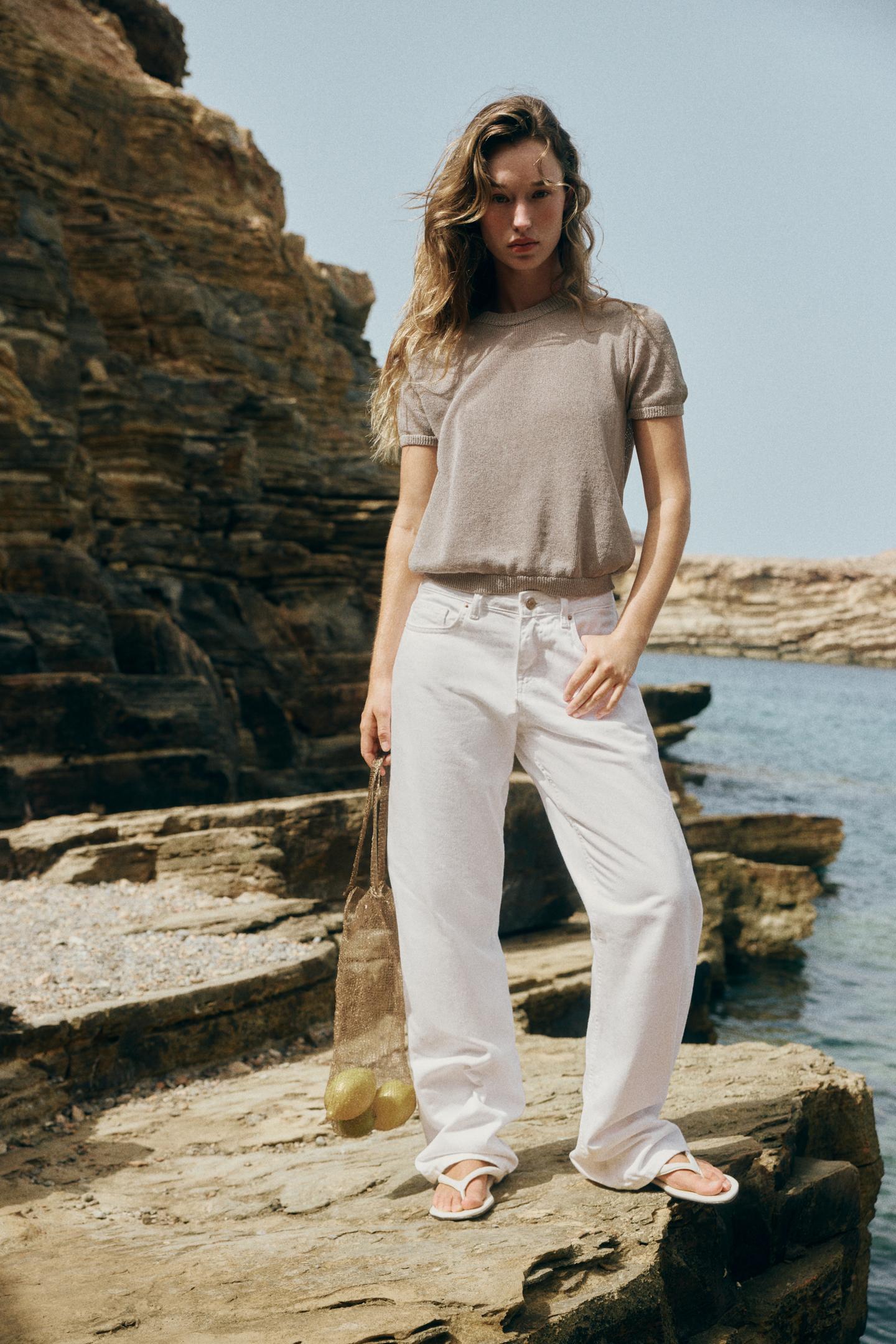 Beige short-sleeve crew neck top set, white wide-leg pants with front pockets, and white sandals.